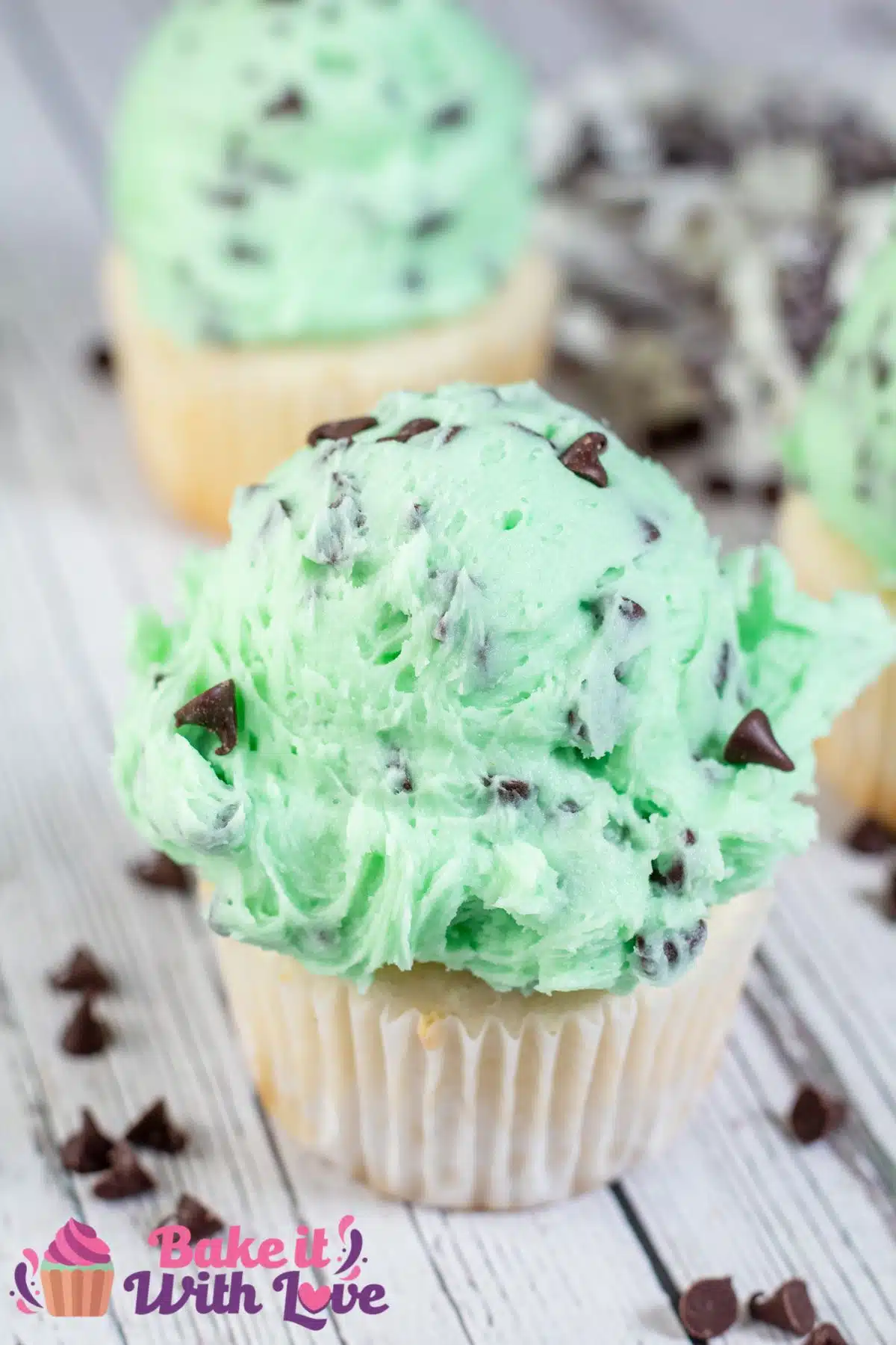 Tall image showing mint chocolate chip buttercream frosting on a cupcake.