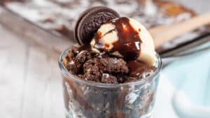 Wide image of Oreo dump cake in a glass dish with ice cream.