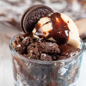 Wide image of Oreo dump cake in a glass dish with ice cream.