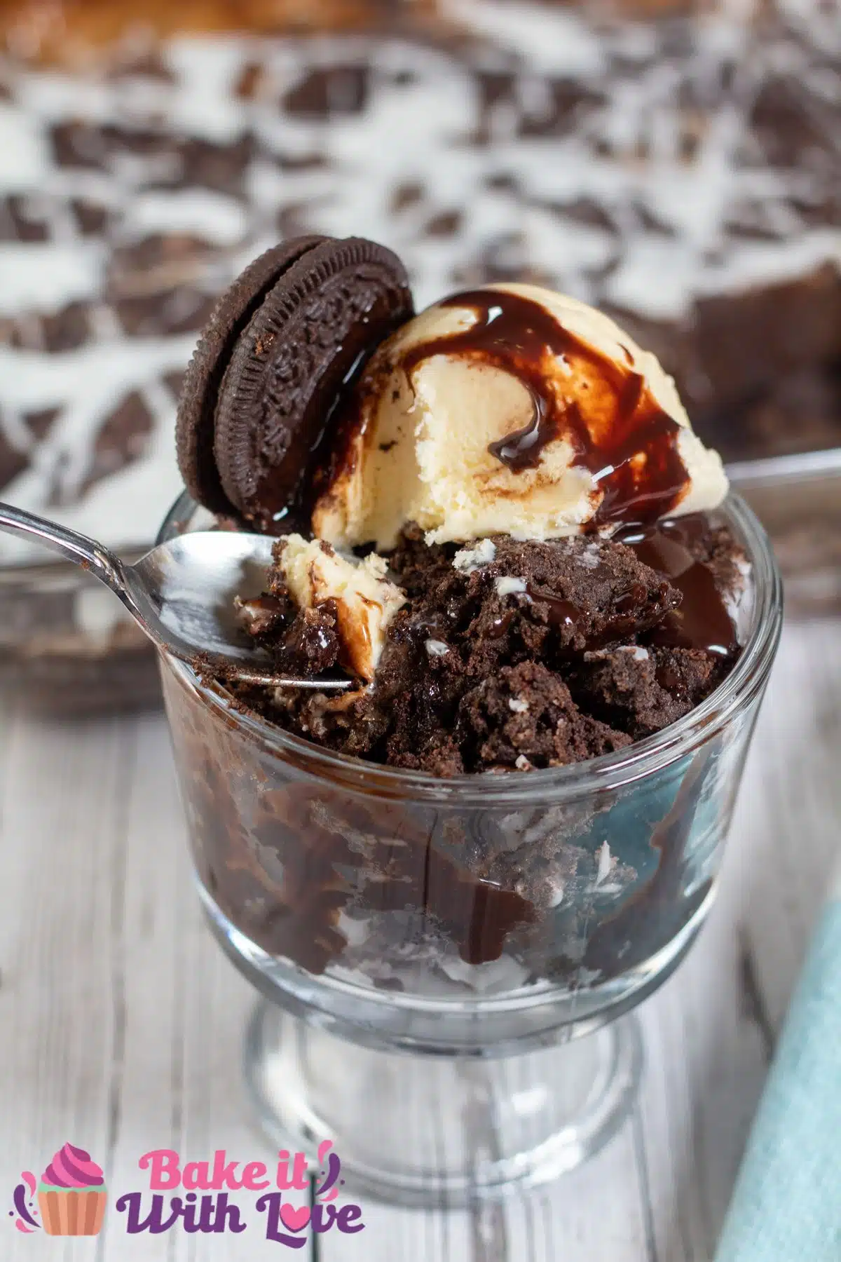 Tall image of Oreo dump cake in a glass dish with ice cream.