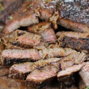 Square image of sliced pan seared chuck steak on a cutting board.