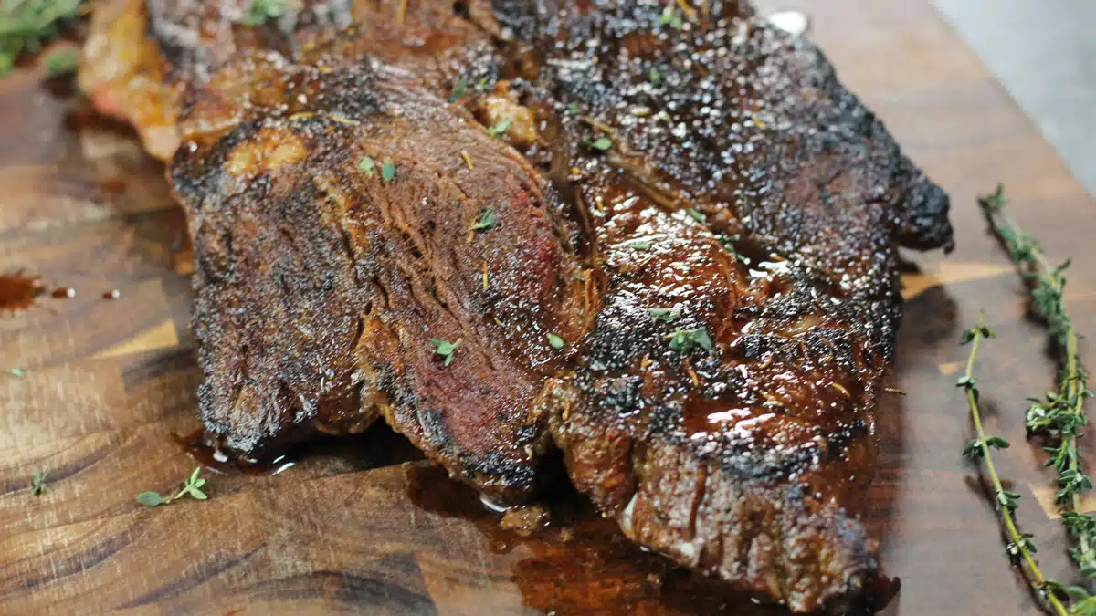 Wide image of pan seared chuck steak on a cutting board.