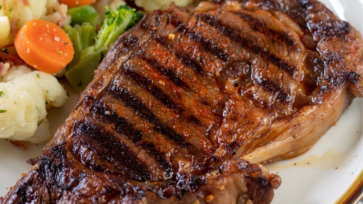 Wide image showing ribeye steak on a plate.