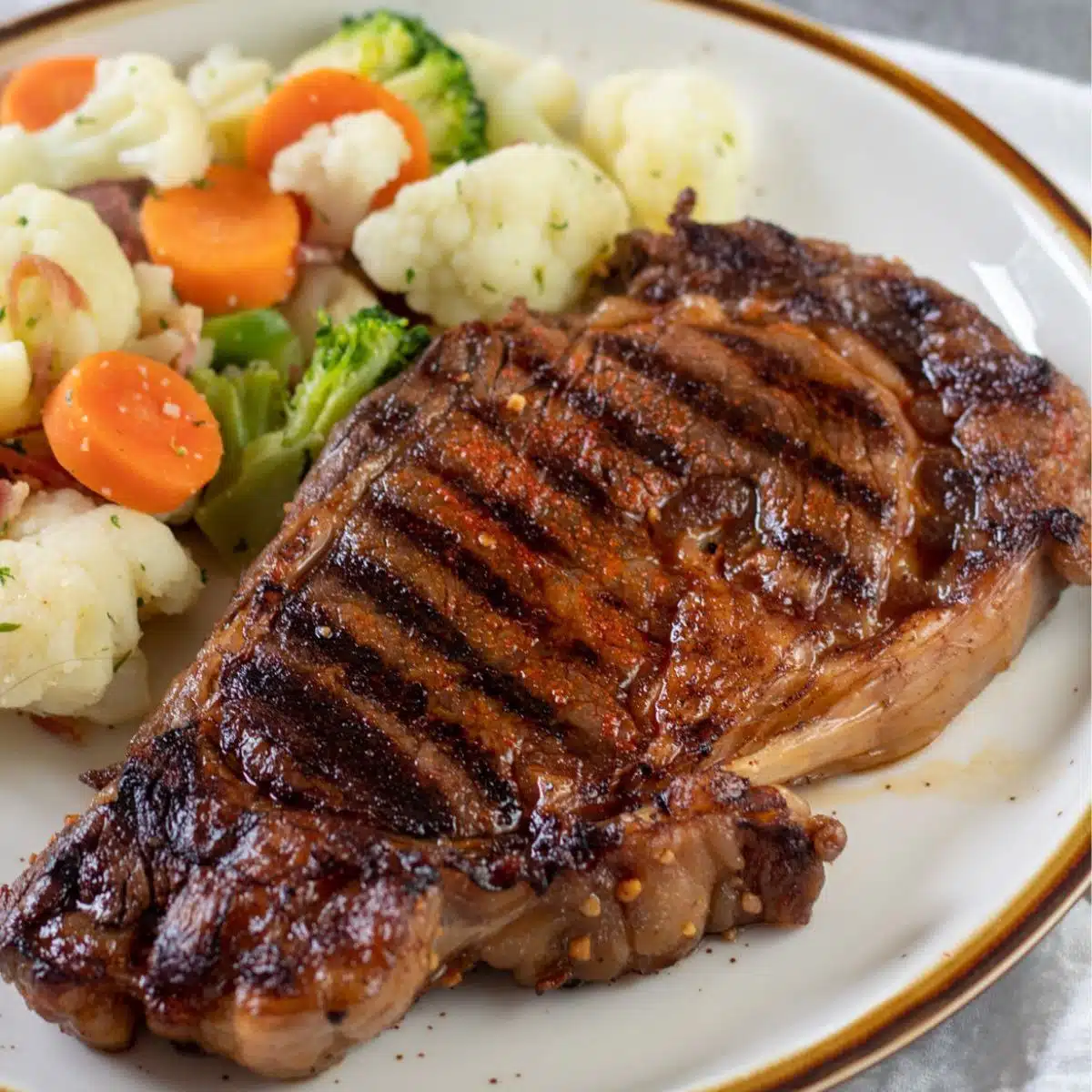 Quadratisches Bild mit Ribeye-Steak auf einem Teller.