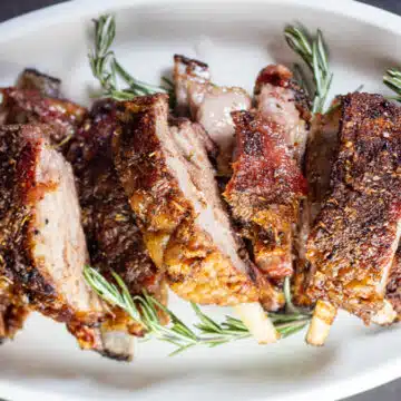 Wide image showing lamb breast ribs on a serving plate.