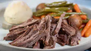 Wide image showing slow cooker London broil on a dinner plate.