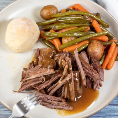 Square image showing slow cooker London broil on a dinner plate.