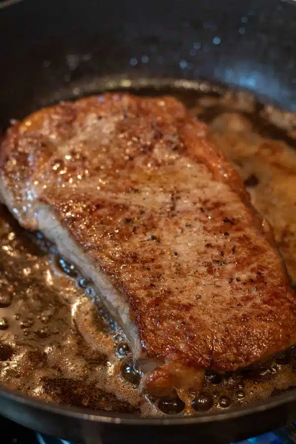 Process image 3 showing other side of steak cooking in pan.