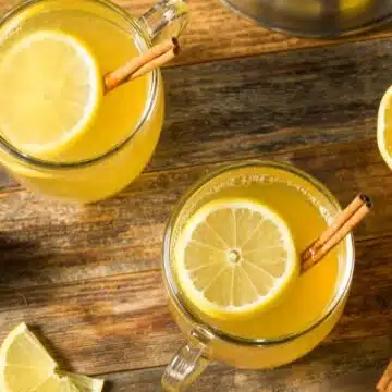 Best hot toddy recipe served in cozy mugs and a slice of lemon with cinnamon stick.