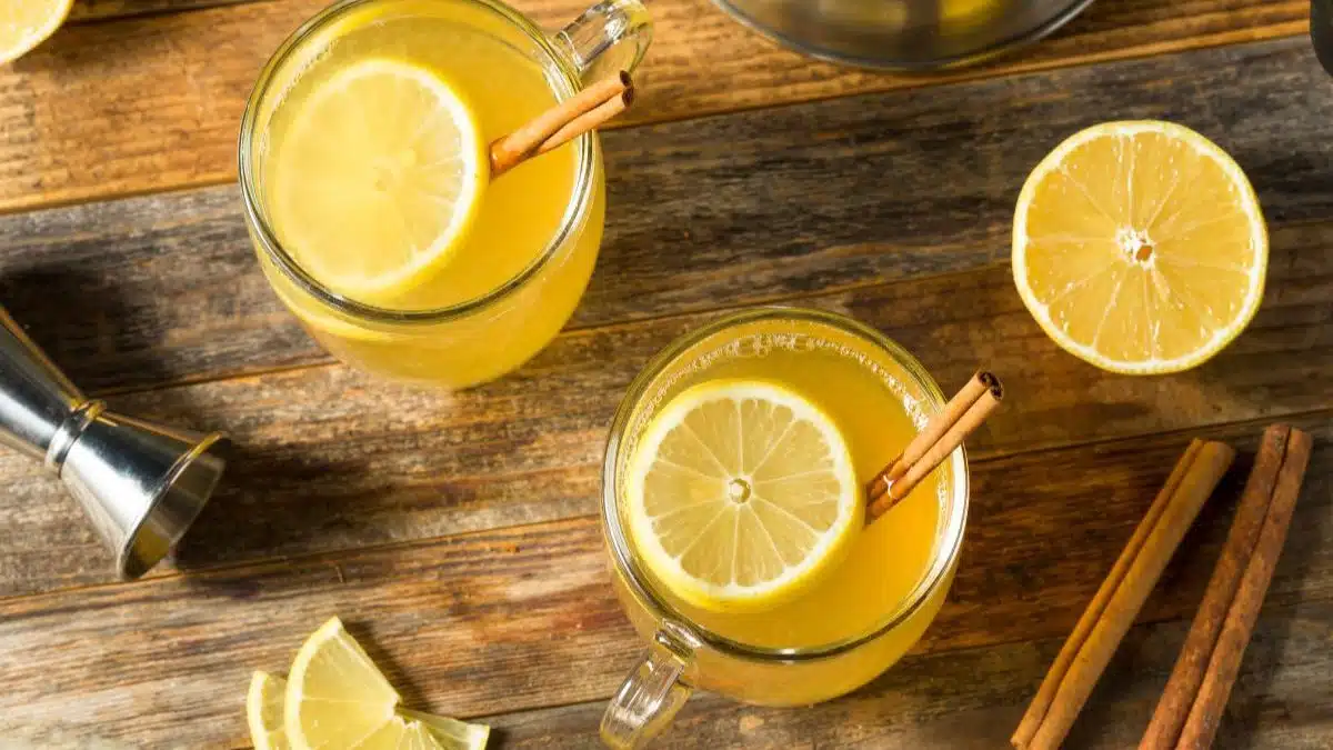 Best hot toddy recipe served in cozy mugs and a slice of lemon with cinnamon stick.