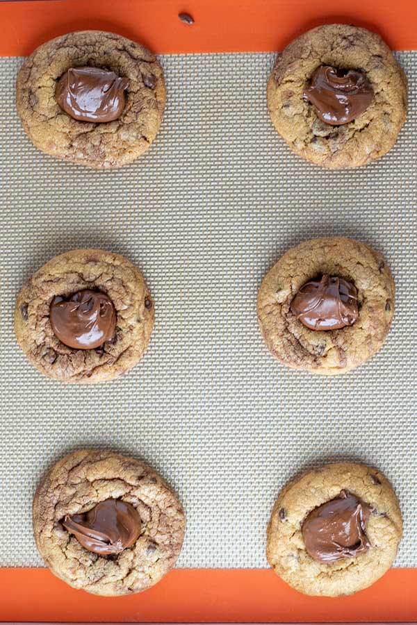 Erdnussbutter-Nutella-Kekse verarbeiten Foto 10 gebackene Kekse mit gefrorenem Nutella-Klecks darauf.