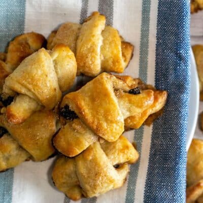 Rugelach rolled filled cookies baked and served on plate lined with kitchen towel.