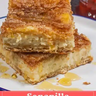 Best sopapilla cheesecake bars recipe pin with stacked plated dessert squares on white plate with honey drizzled over them.