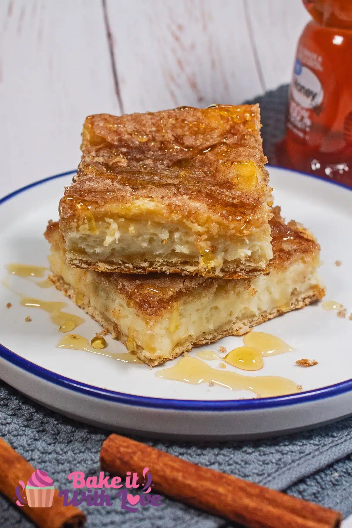 Best sopapilla cheesecake bars served on a plate with honey drizzled over two squares.