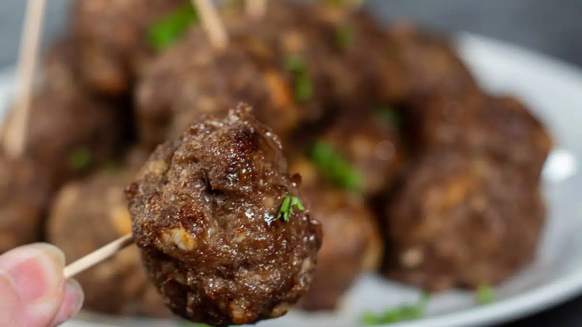 Close up wide image showing air fryer meatballs on a white plate.