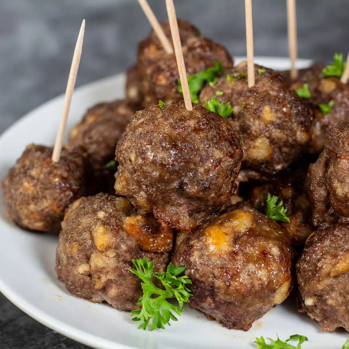 Square image showing air fryer meatballs on a white plate.
