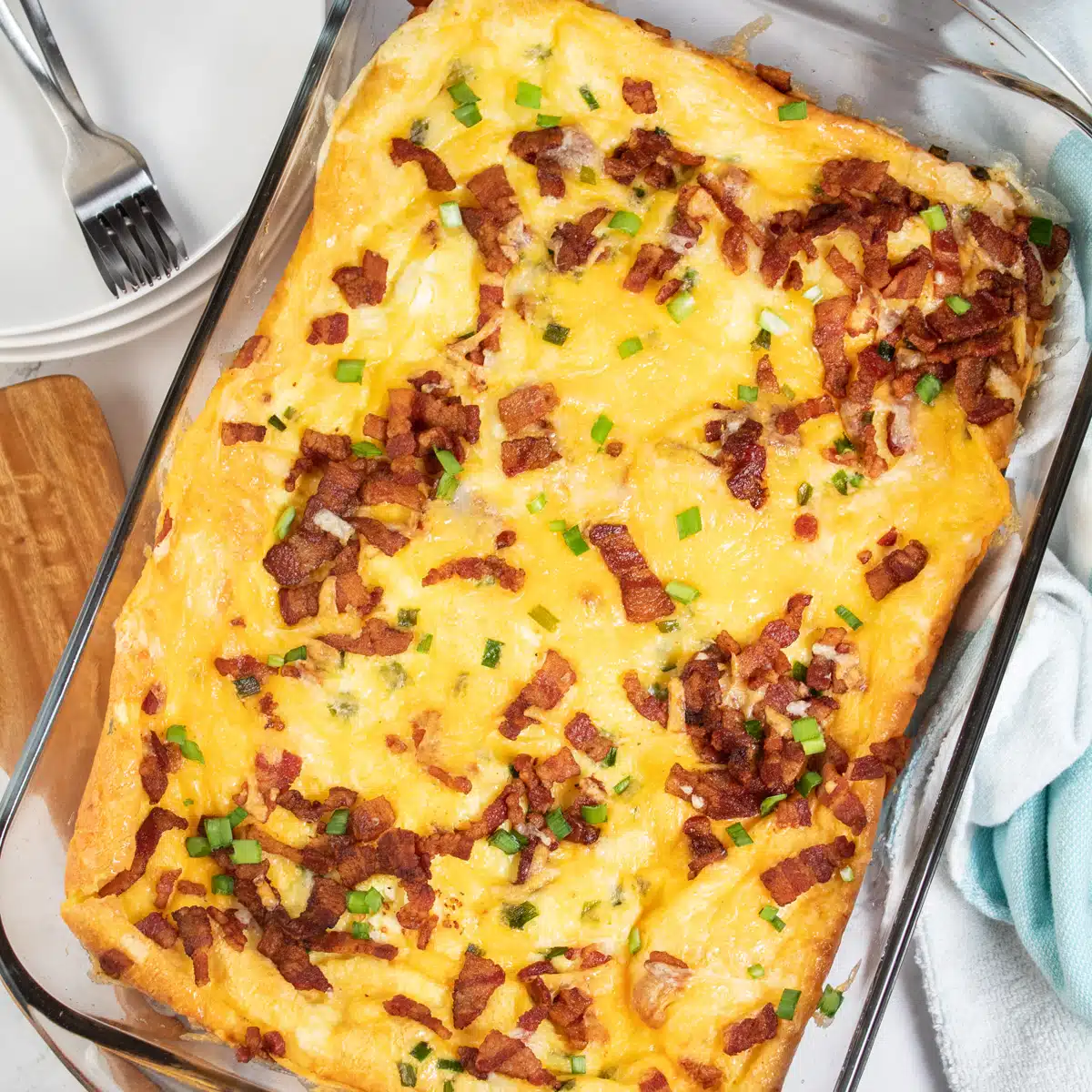 Square image of bacon breakfast casserole in a glass baking dish.