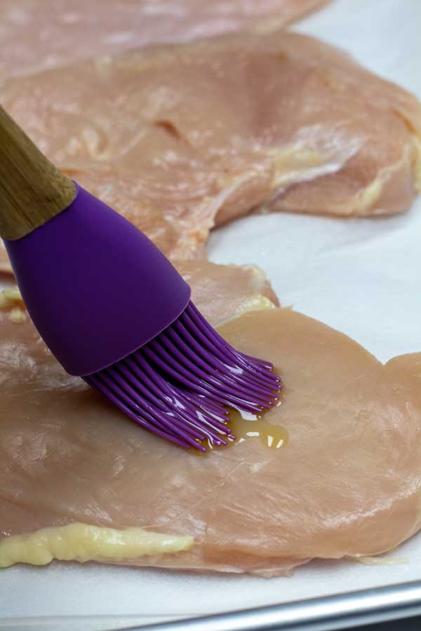 Processe a imagem 2 mostrando pincelar óleo nos peitos de frango.