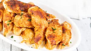 Ampia immagine di filetti di pollo al forno su un piatto bianco.