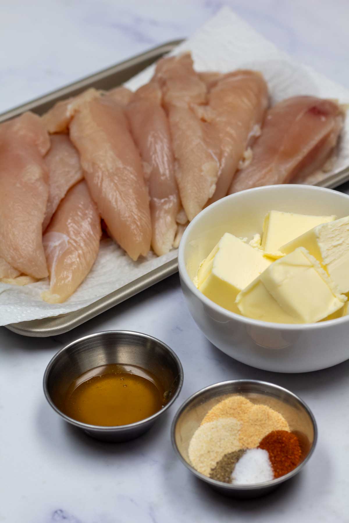 Imagen alta que muestra los ingredientes para filetes de pollo al horno.