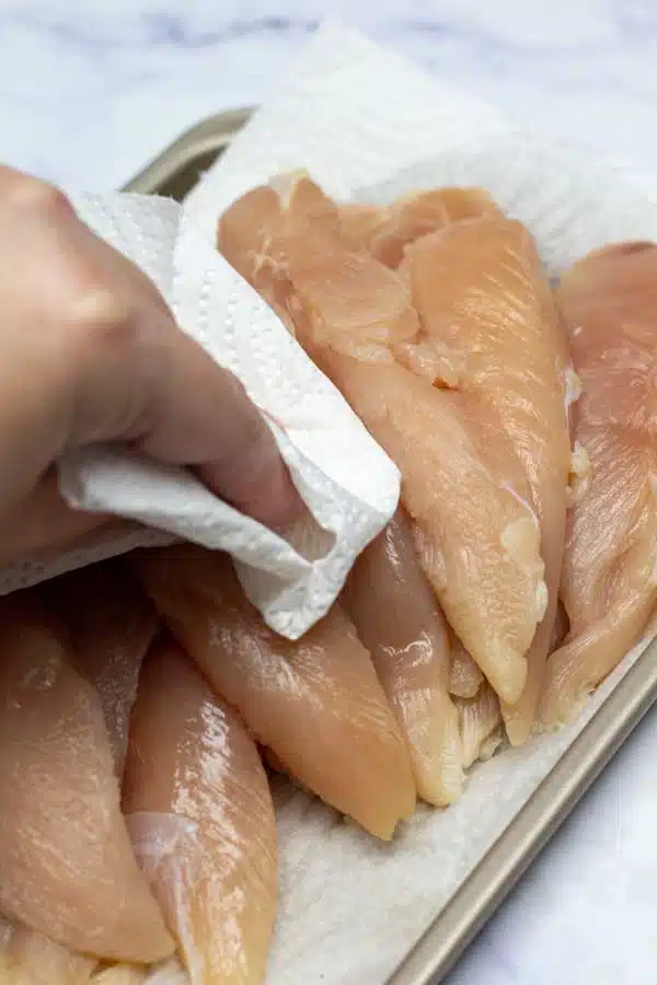 Process image 1 showing patting chicken tenderloins dry.