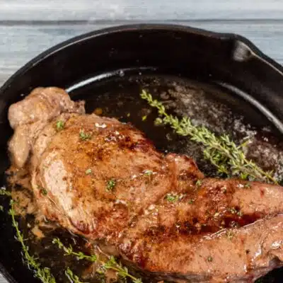Pin image with text of baked chuck steak in a cast iron pan.
