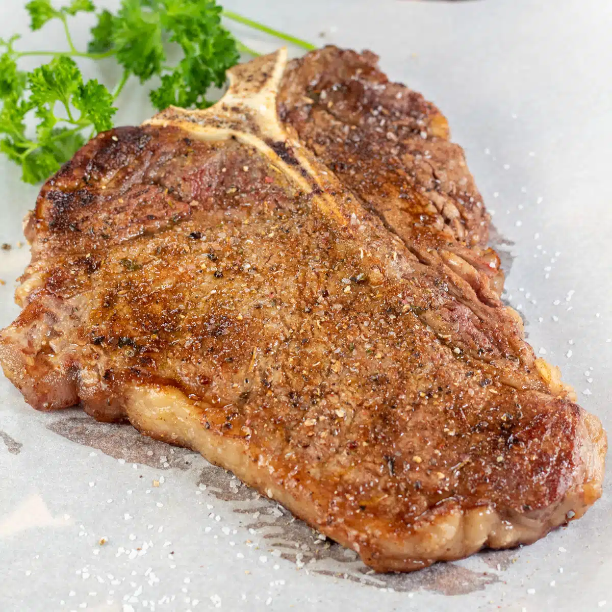 Square image showing baked t bone steak.