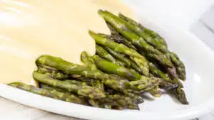 Wide image showing cheese sauce on asparagus.