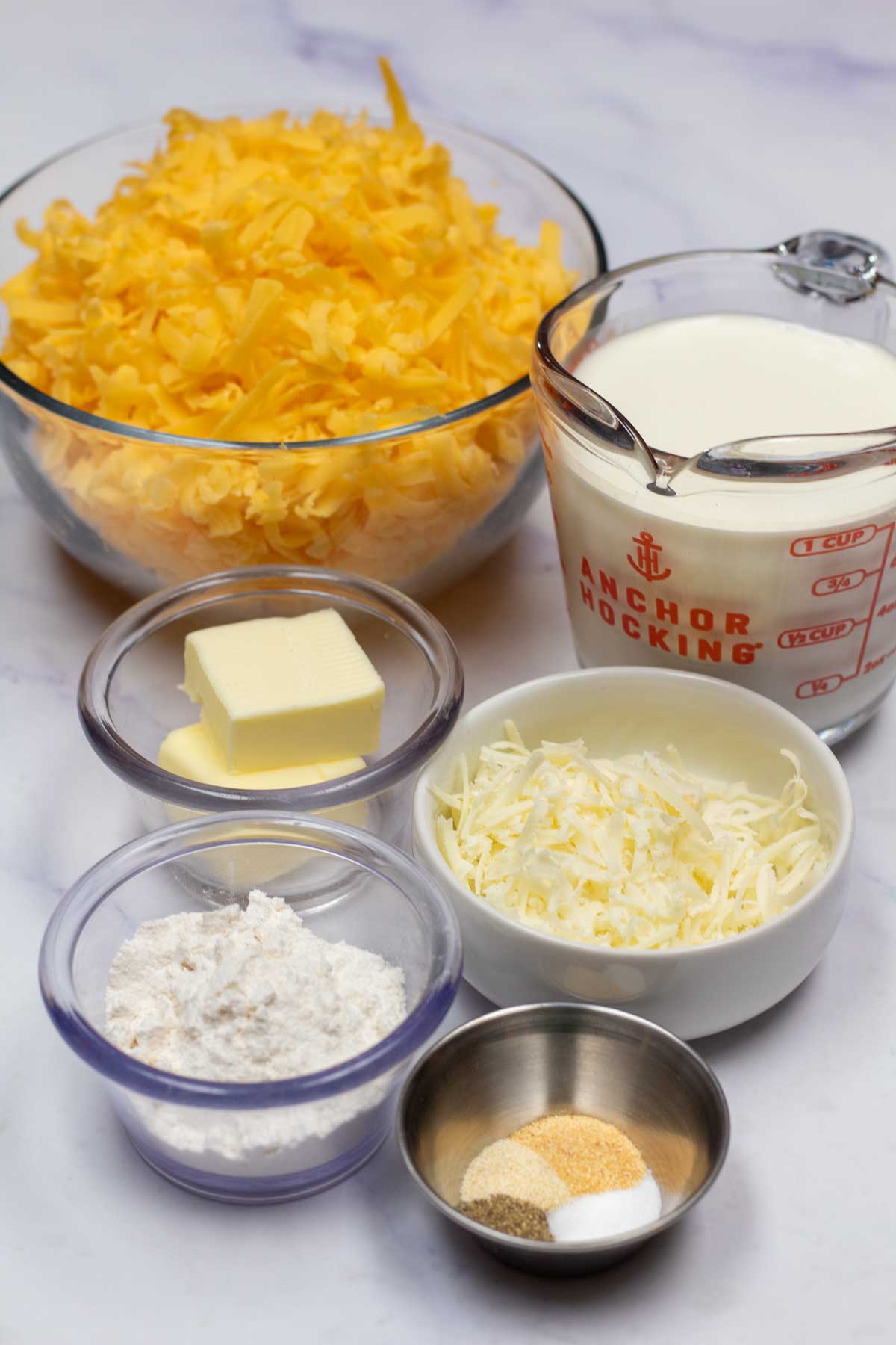 Vysoký obrázek zobrazující ingredience potřebné pro sýrovou omáčku.