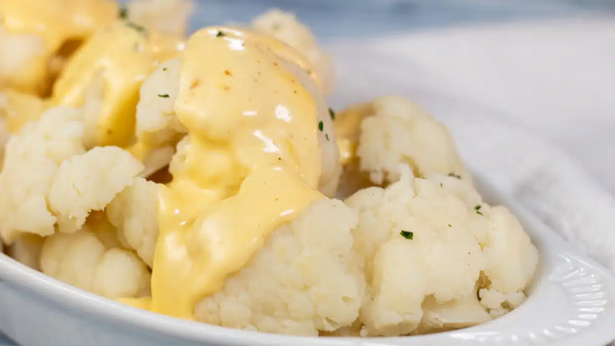 Wide image of cauliflower covered with cheese sauce.