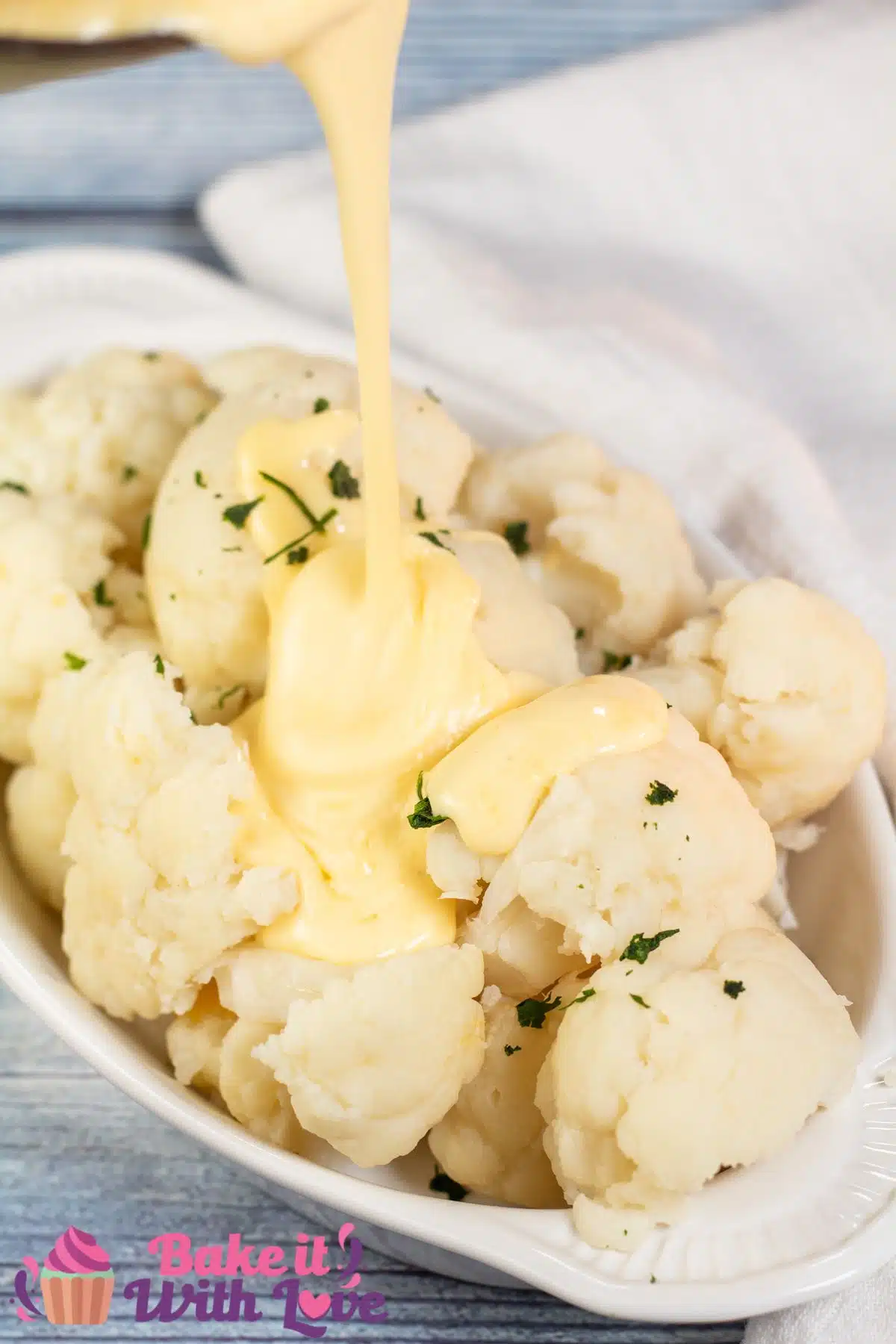 Tall image of cauliflower covered with cheese sauce.