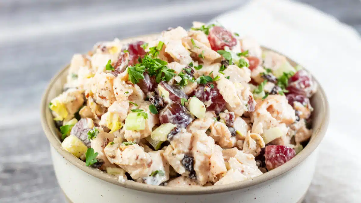 Wide image of a bowl of chicken salad with grapes.