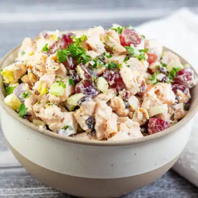 Square image of a bowl of chicken salad with grapes.