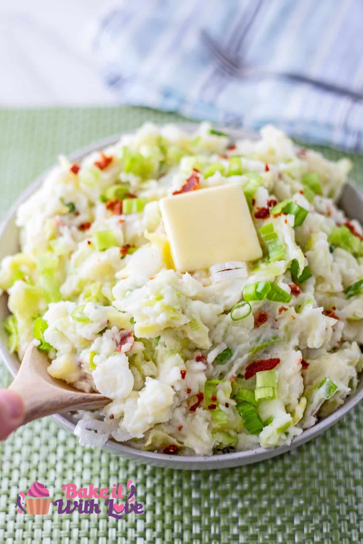 Tall image showing colcannon in a bowl with a wooden spoon sticking out.