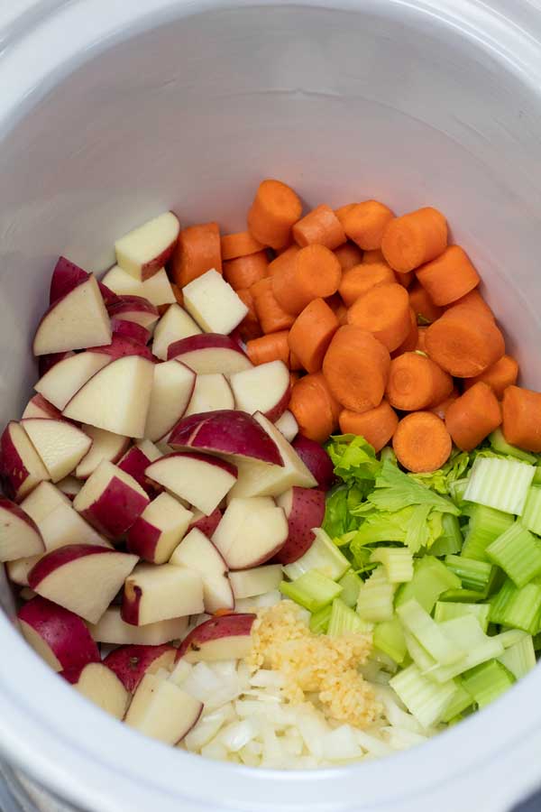 Изображение процесса 2, показывающее картофель, лук, морковь и сельдерей в мультиварке.