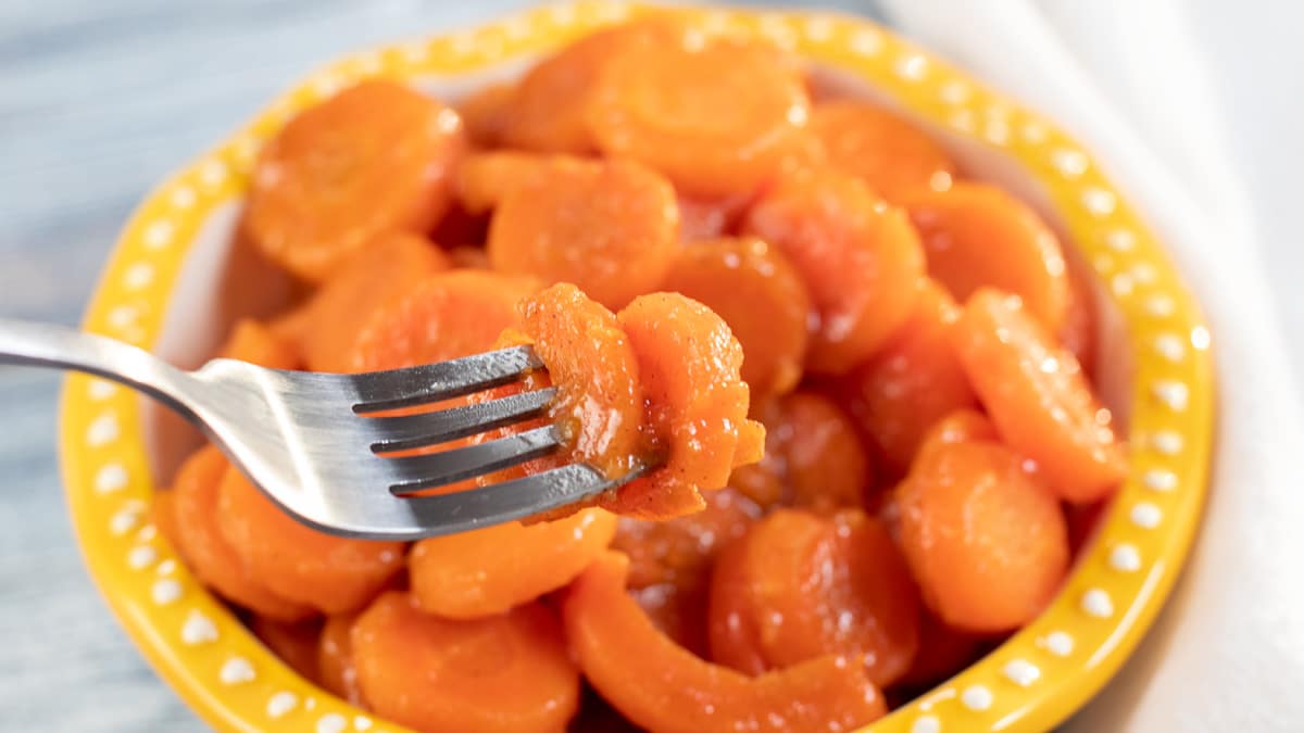 Wide image showing canned cooked carrots in a bowl.