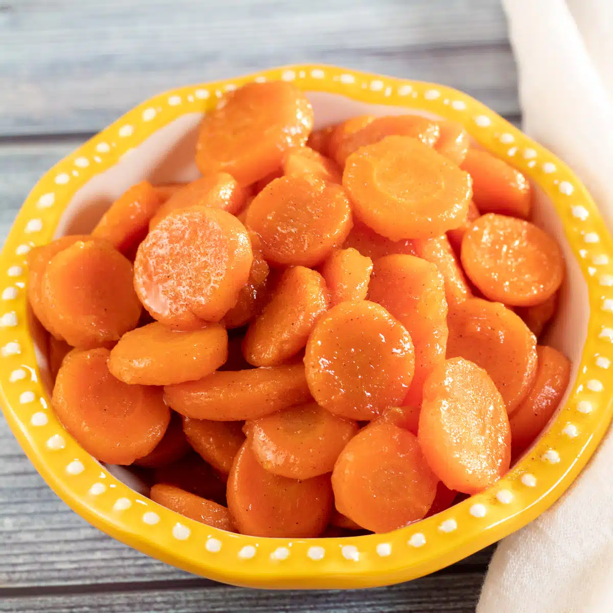 Square image showing canned cooked carrots in a bowl.