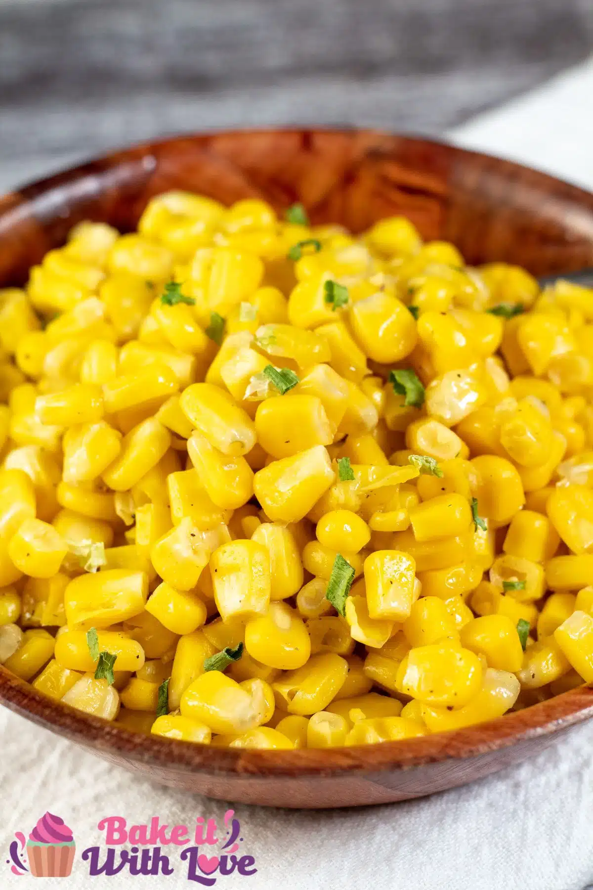 Tall image showing cooked canned corn in a wooden bowl.