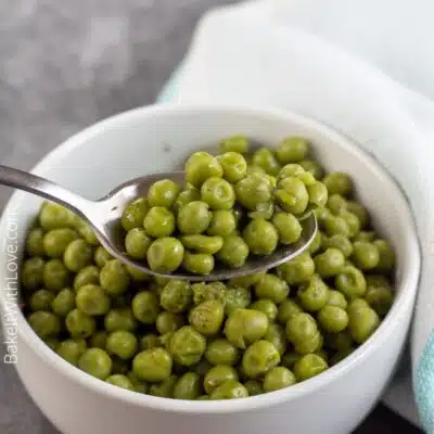 Pin image showing canned cooked peas in a small white bowl.