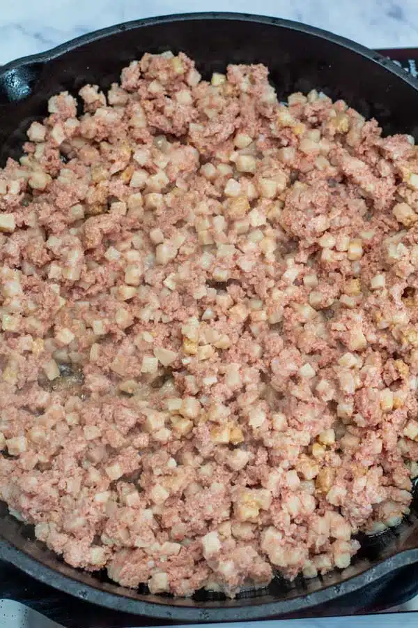 Process image 1 showing canned corned beef hash in skillet.