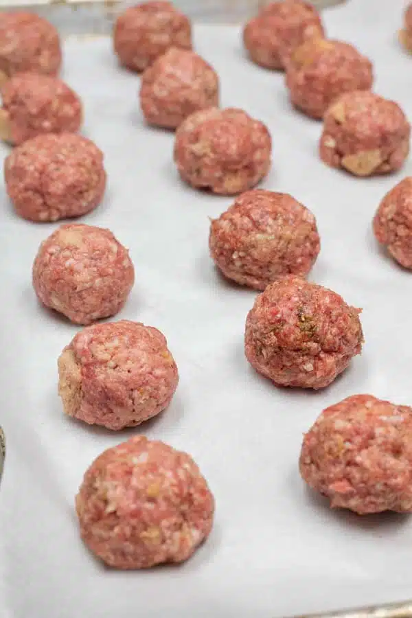 Process image 3 showing rolled raw lamb meatballs on a baking tray.