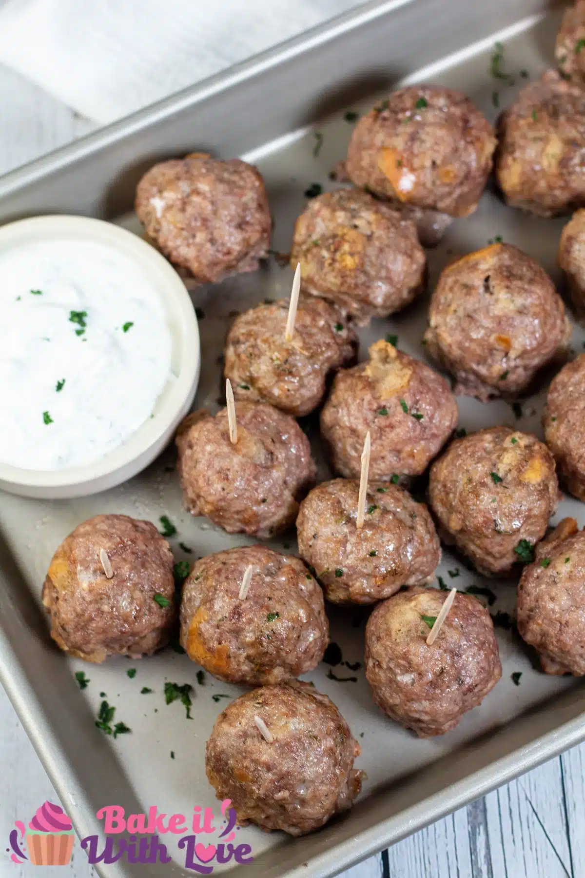 Tall image showing lamb meatballs on a metal tray with dipping sauce.