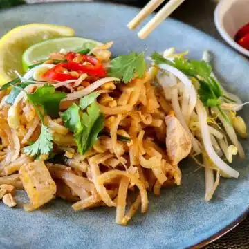 Wide image of pad thai on a blue plate.