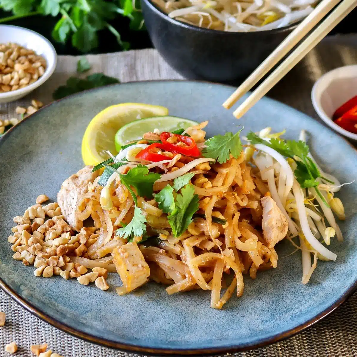 Square image of pad thai on a blue plate.