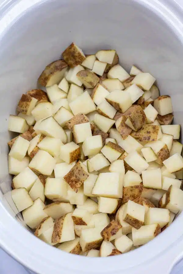 Process image 2 showing cubed potatoes in a crockpot.