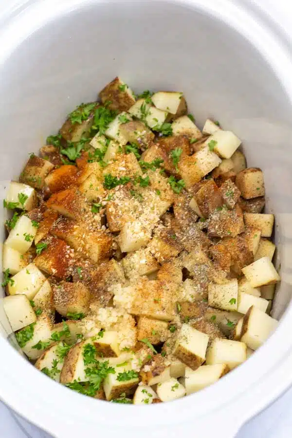 Process image 3 showing cubed potatoes in a crockpot with seasoning.