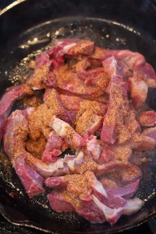 Process image 3 showing steak strips and seasoning in pan.