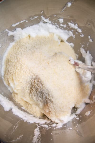 Les biscuits Amaretti traitent la photo 5, ajoutez de la farine d'amande tamisée et du sucre par portions, puis incorporez-les aux blancs d'œufs.