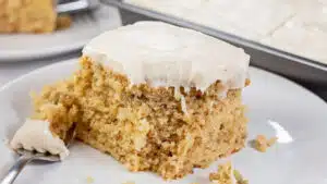 Tasty banana cake with cinnamon cream cheese frosting sliced and served on white plate.