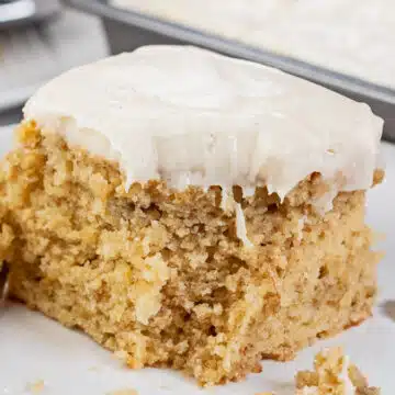 Tasty banana cake with cinnamon cream cheese frosting sliced and served on white plate.
